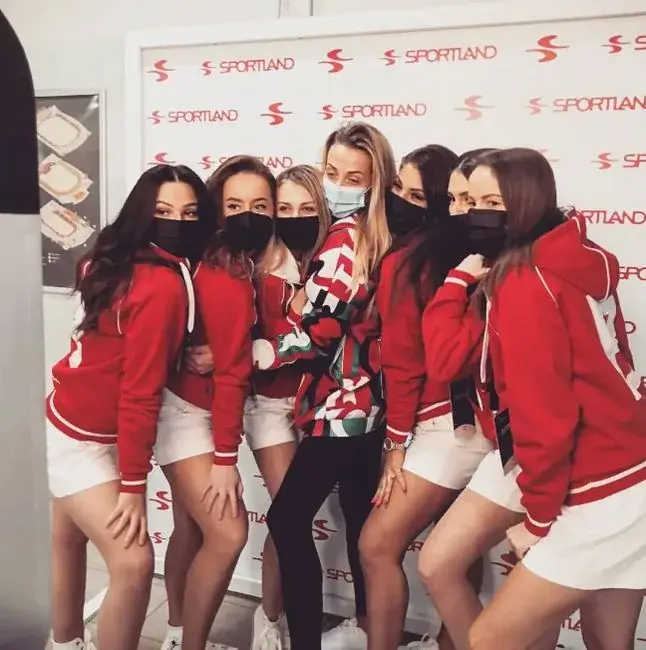 Sportland komanda sarkanās jakās pie zīmola foto sienas